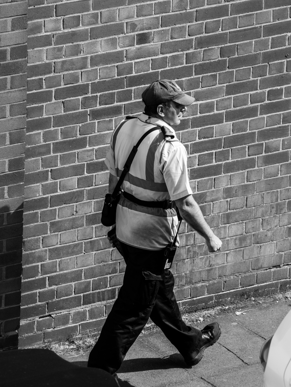 a postman walking along the road with harsh shadows